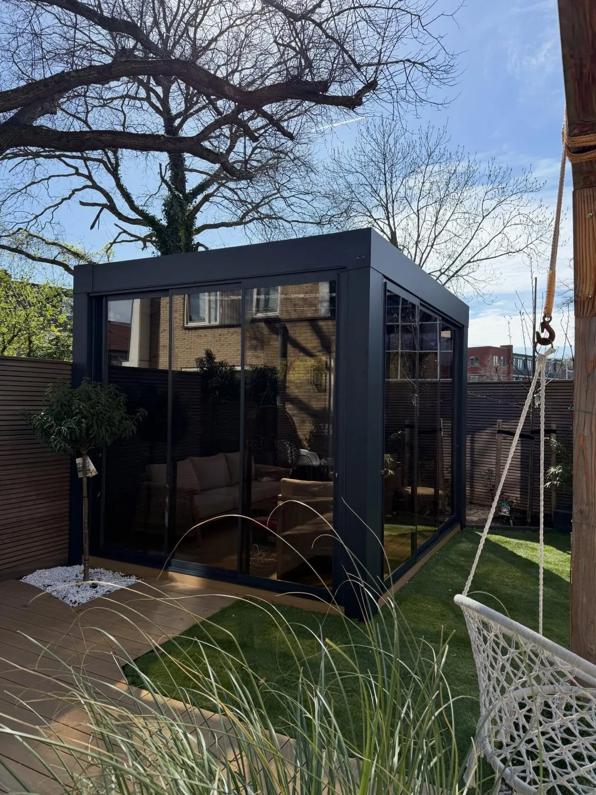 Vrijstaande cube veranda met heldere glazen wanden in een stadstuin